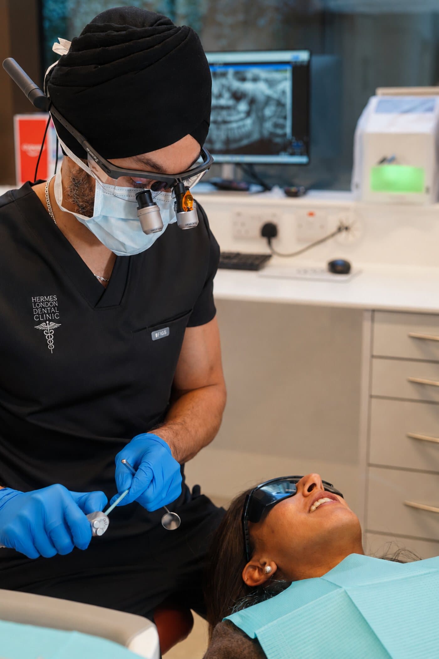 A dentist treating a patient in the chair at Hermes London Dental Clinic